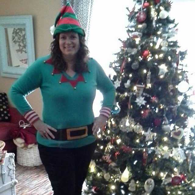 me, dressed as an elf, standing beside our Christmas tree