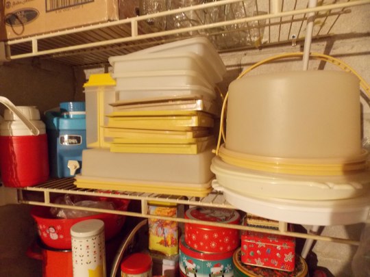 Stacks of neatly organized vintage tupperware and tins, on shelves.